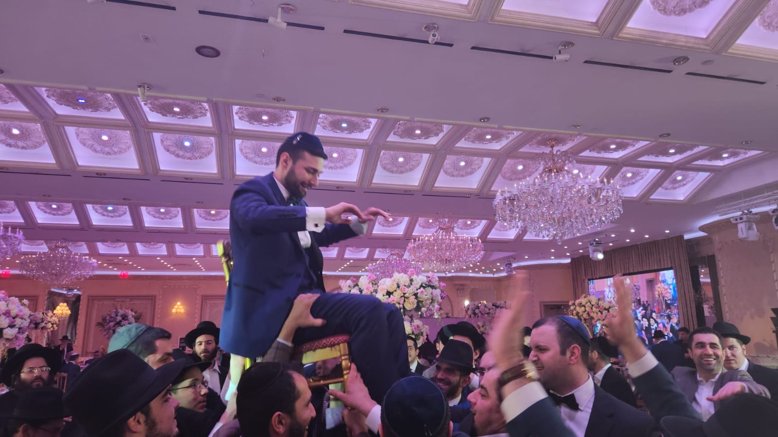 A chosson lifted on a chair as talmidim dance around him