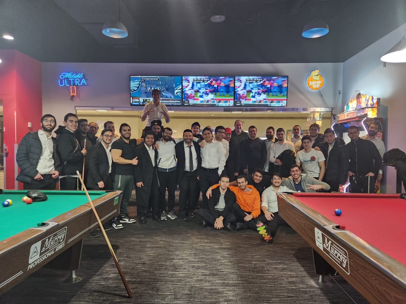 A group of talmidim posing between pool tables on a night out
