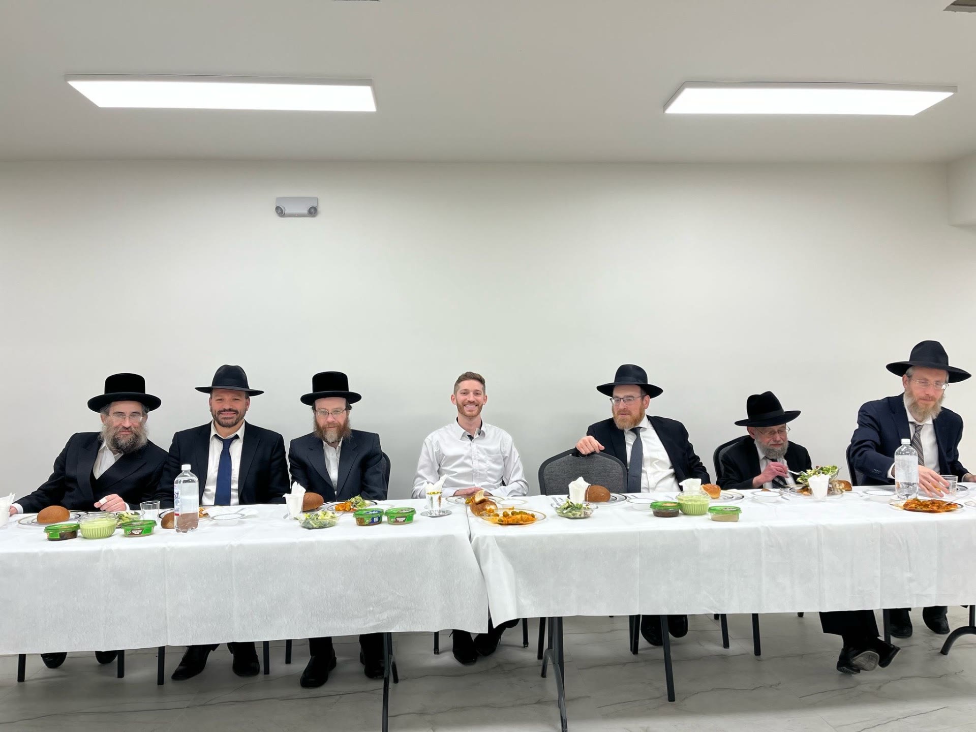 Rebbeim and guests seated together at the head table of a meal
