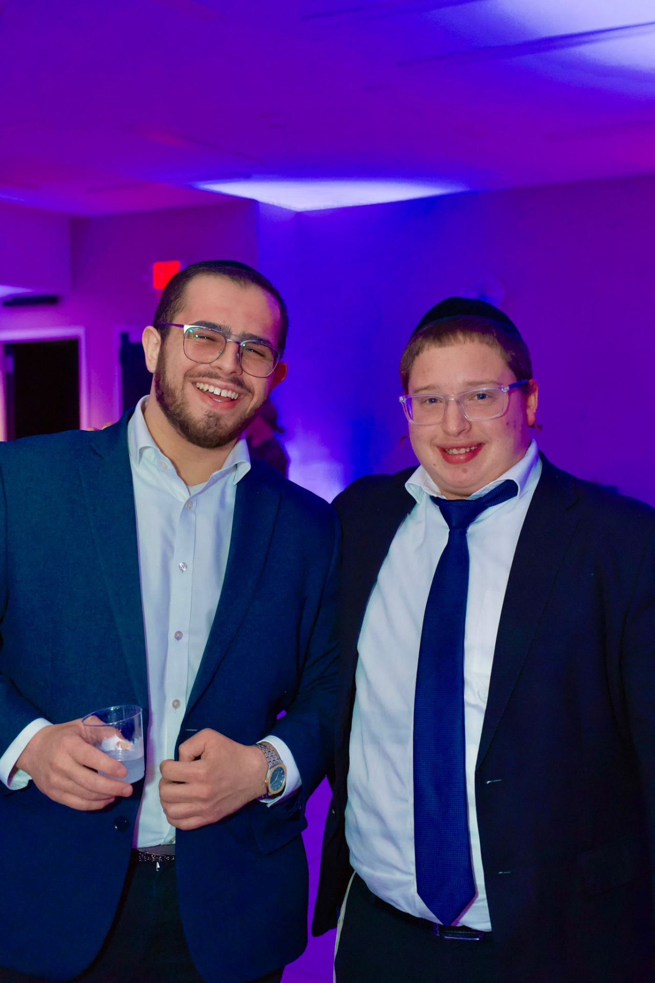 Two talmidim smiling together at an evening celebration