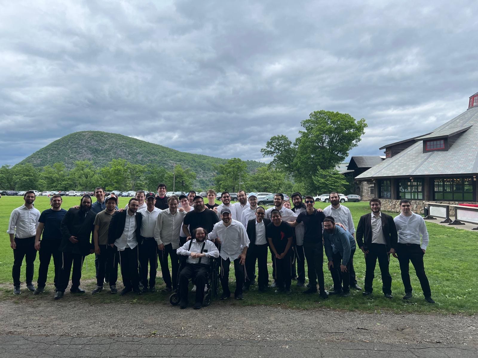 The whole group posing outdoors on the grass with a mountain behind them