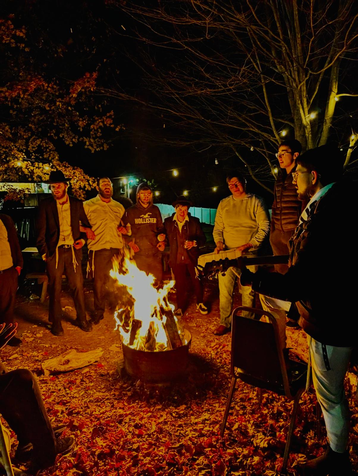 Talmidim singing together around an outdoor fire at night
