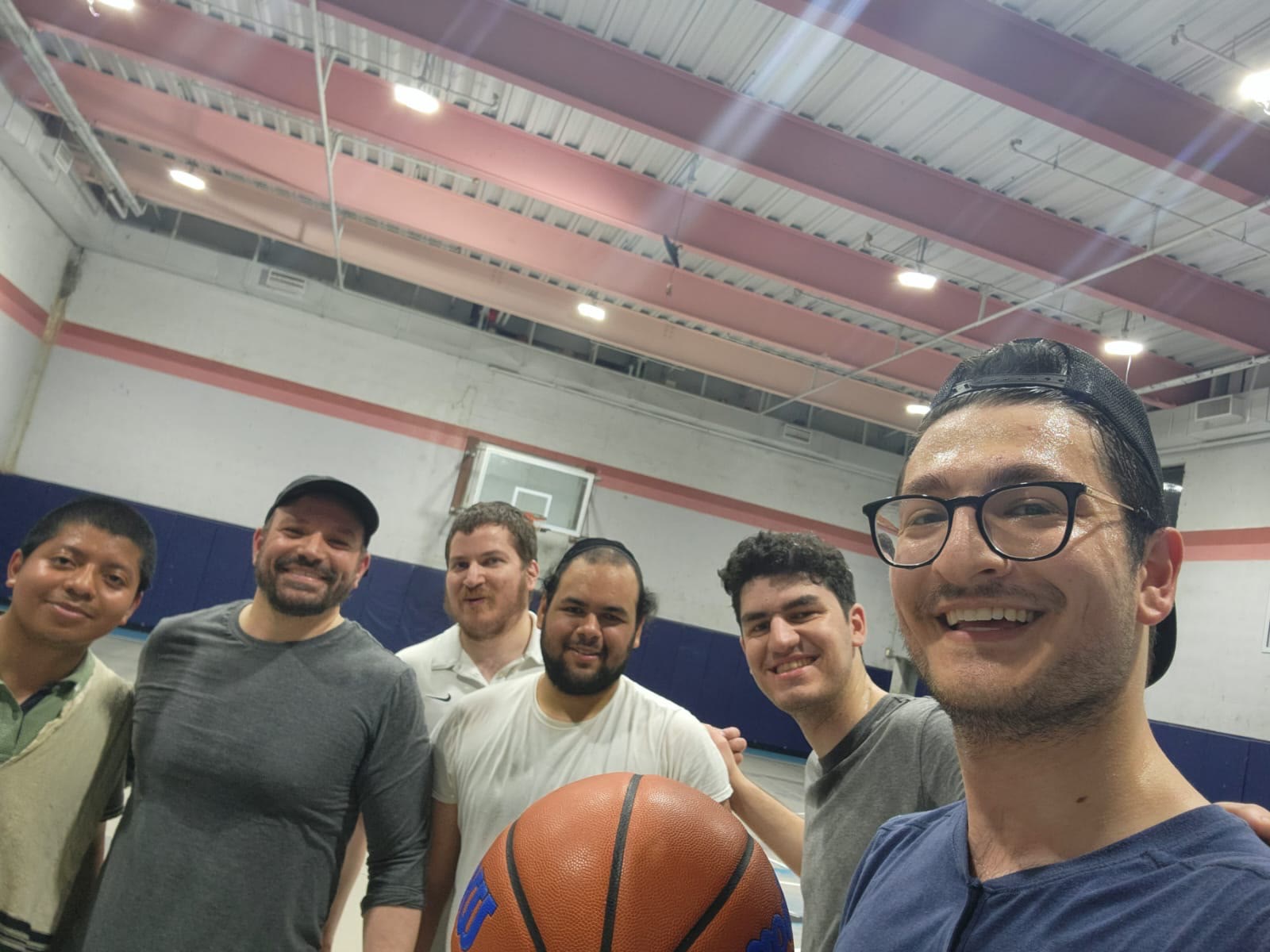 Talmidim posing with a basketball in the gym