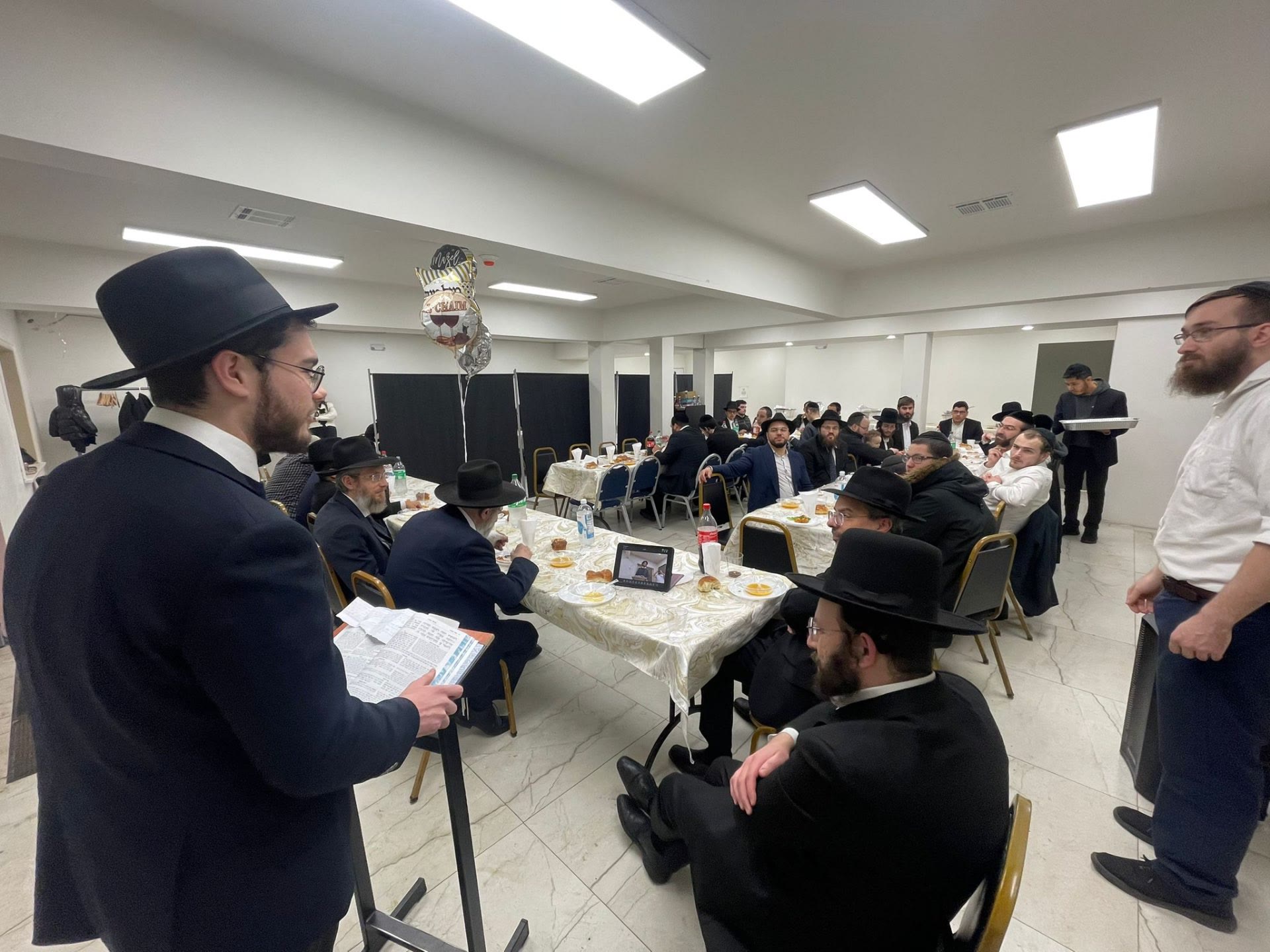 A talmid speaking at a shtender during a celebratory meal