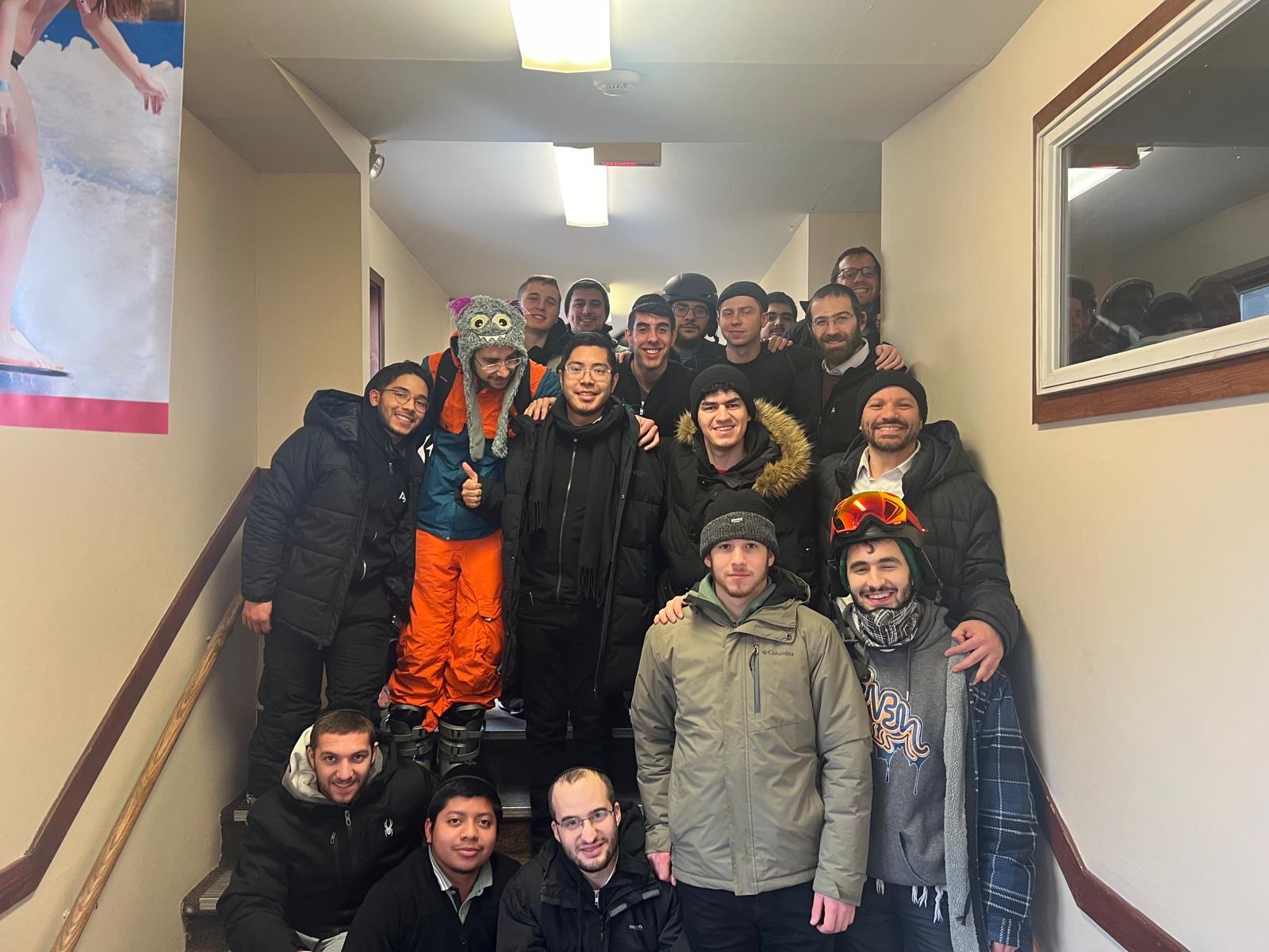 Talmidim in winter gear posing on a staircase at a ski lodge