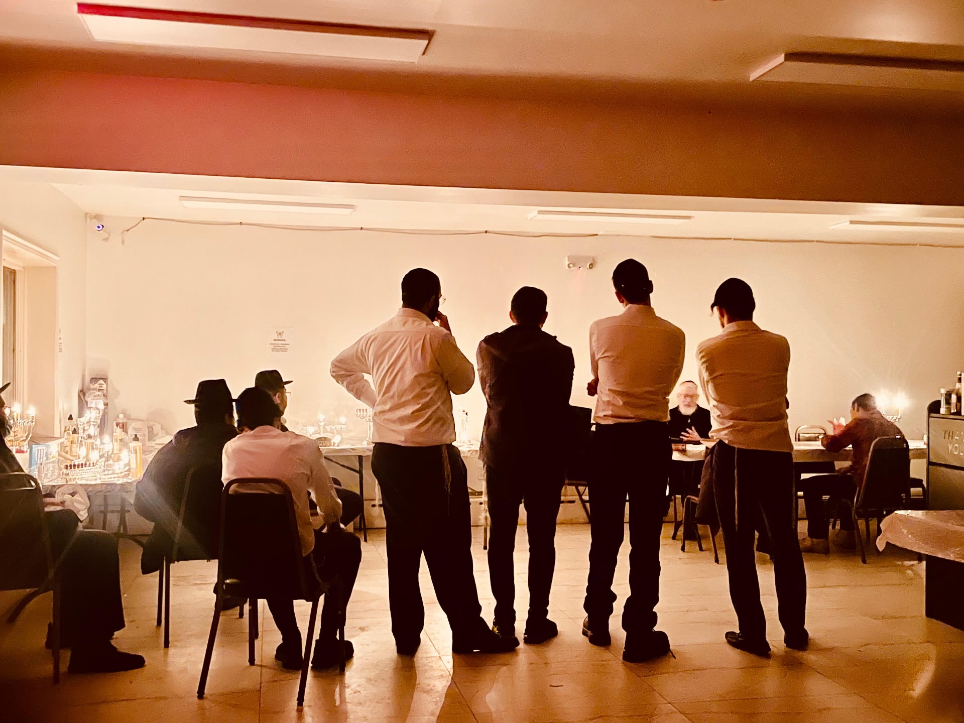 Talmidim standing before a row of lit menorahs