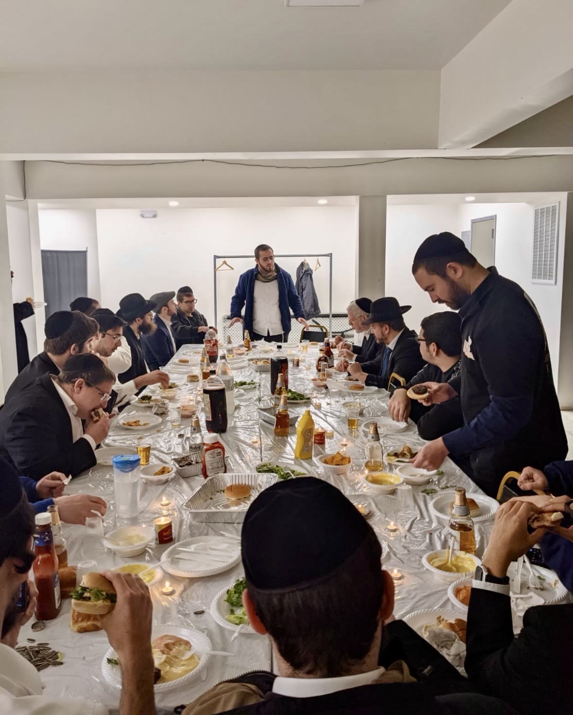 A talmid speaking to the room at a yeshiva meal