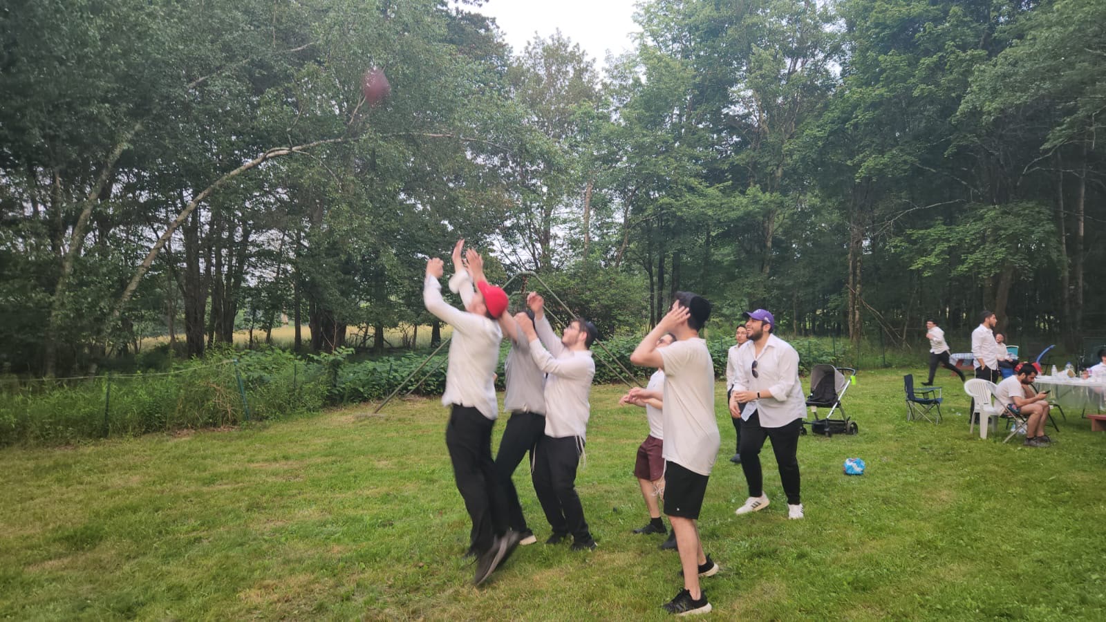 Talmidim jumping for a football on a grassy field