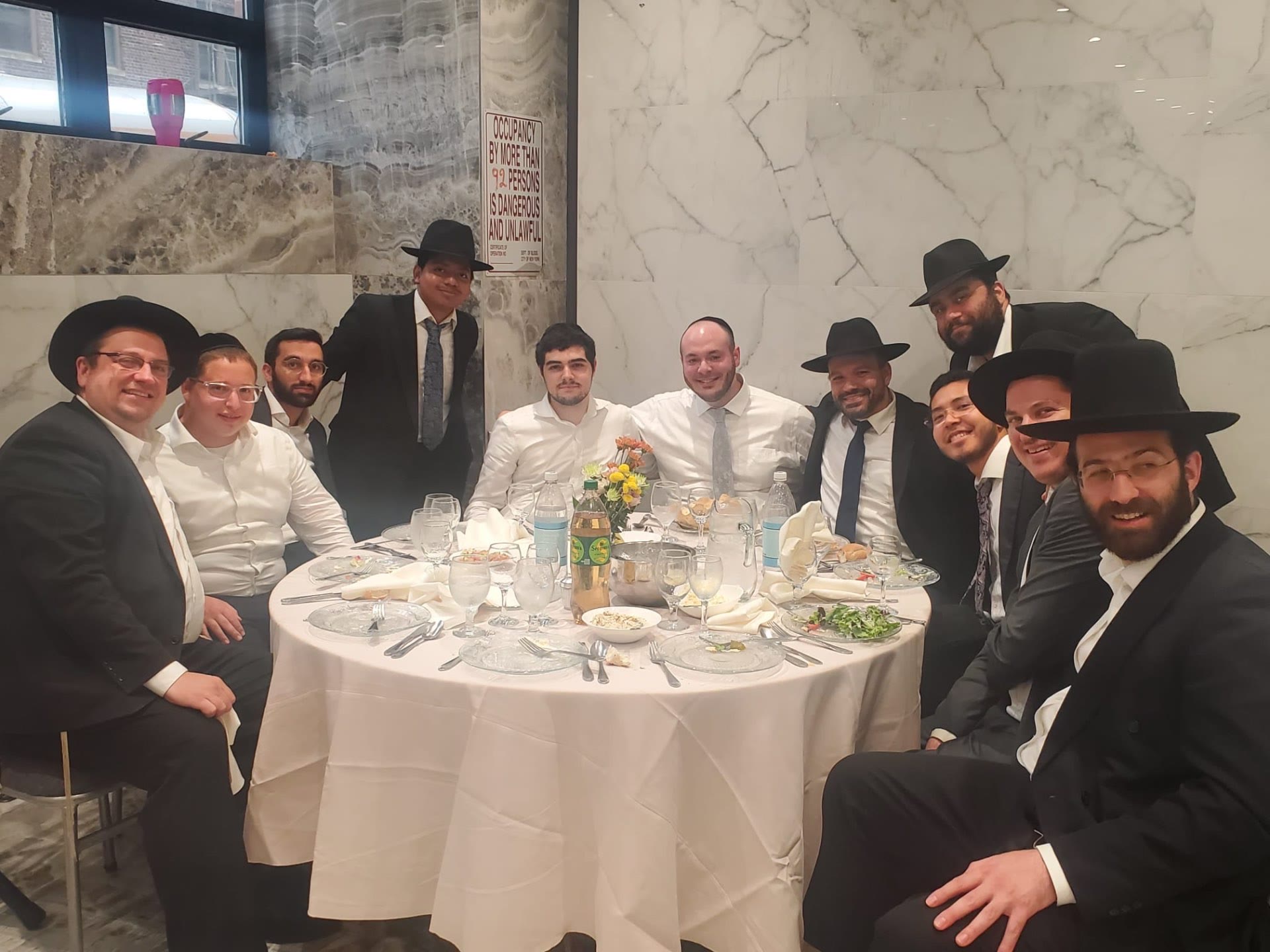 Talmidim and rebbeim seated together at a round table at a simcha